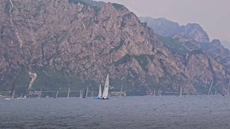 sailing yachts compete in regatta on lake garda with mountain backdrop