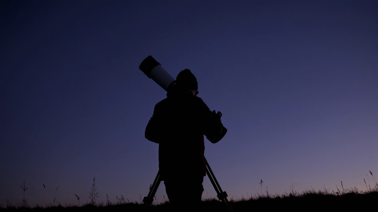 Silhouette di una persona che osserva le stelle con un telescopio di notte