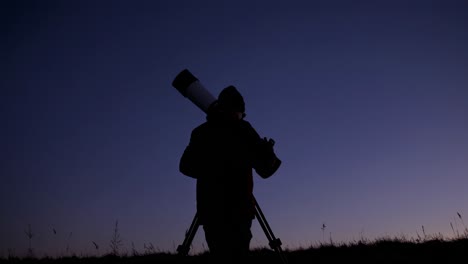 silhouette of a person stargazing with a telescope at night