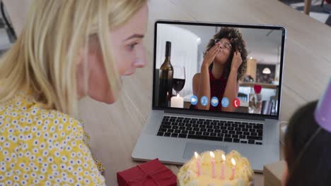 caucasian mother and daughter sitting at table using laptop having birthday video call