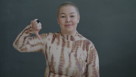woman with thumbs down and neutral facial expression