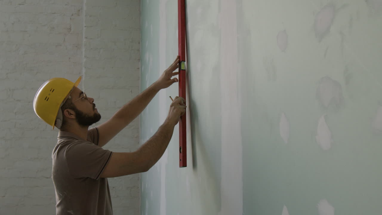 Construction worker using a level on a wall