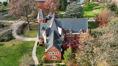 aerial tilt down on gothic architecture building on college university campus during autumn