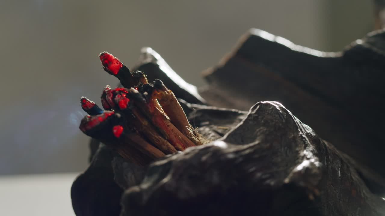 Person holding Palo Santo wood stick in hand, aromatic Palo Santo burning on black background, smoke spreading around, slow motion video clip, high quality 4k close up footage. High quality 4k footage