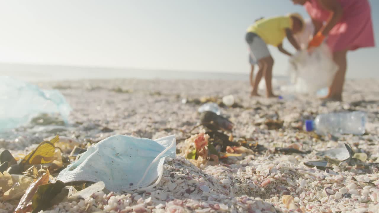 손자들과 함께 아프리카계 미국인 부부가  ⁇ 니 비치에서 쓰레기를 분리하고 있습니다.