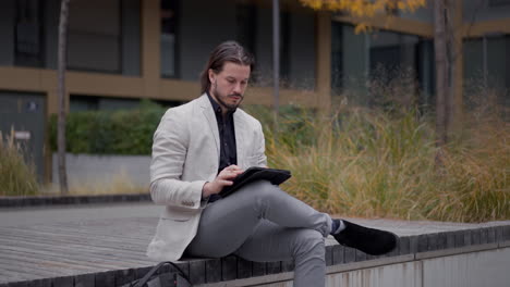 employee man drinking coffee and working tablet computer at the street