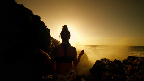 woman meditating on a rocky beach at sunrise