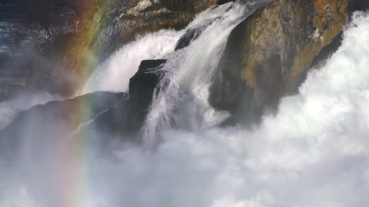 Colorful rainbow over waterfall and rocks. handheld