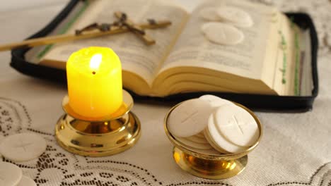 communion hosts lit candle and holy bible cross with jesus