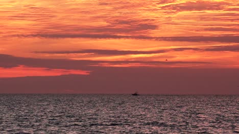 twilight on the ocean with a luxury fishing boat and bird flying in the distance