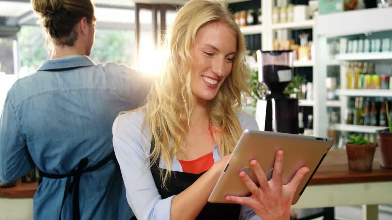 Smiling waitress standing at counter using digital tablet