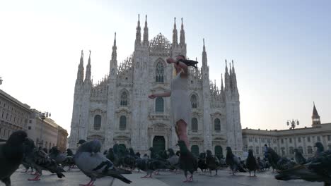 blonde female model in front of the milan cathedral duomo playing with pigeons on a summer morning day in milan, italy