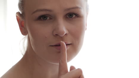 retrato de una mujer joven mostrando el gesto del silencio