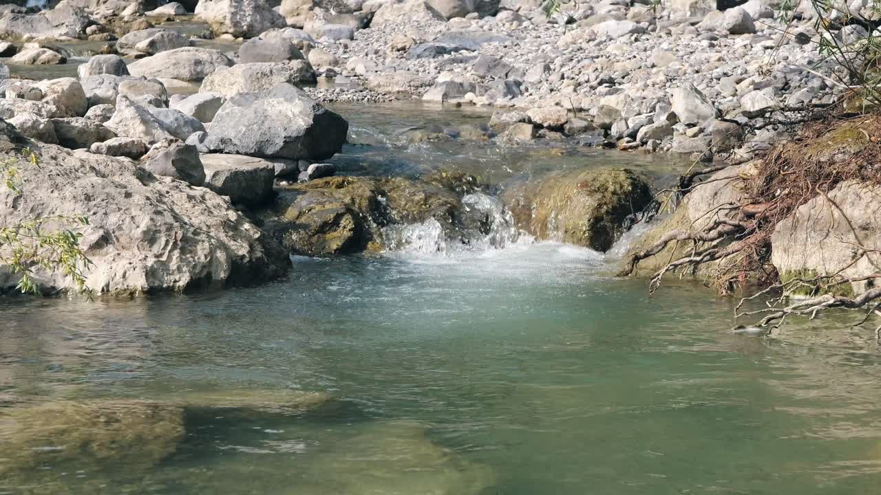 imagen estática de un río con agua clara y corriente y piedras