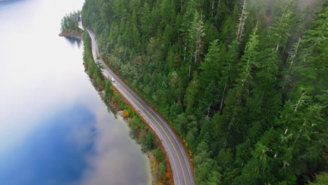 Beautiful-Coastal-Road-Along-River-Shoreline-Through-Pine-Forest-Mountains-in-Port-Alberni-Region,-British-Columbia-Canada,-Aerial-View