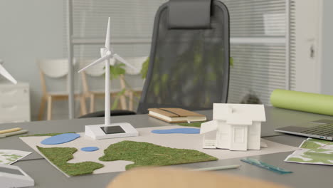 miniatura de turbina eólica y modelo de casa en la mesa de la oficina