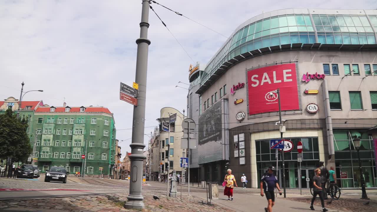 Panning shot of Kupiec Poznanski shopping mall and people walking on the street