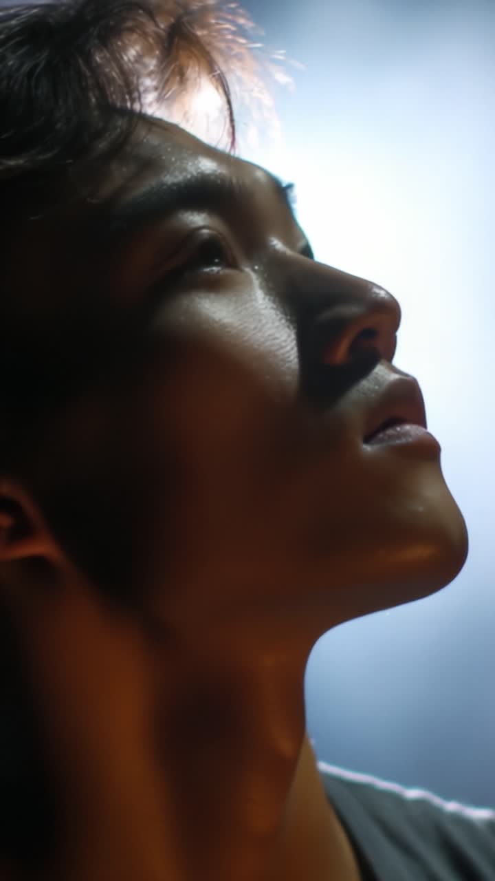 A Profile of Determination: Captivating Close-Up of a Young Man Gazing Upward with Intensity in a Dramatic Light Setting Highlighting His Features