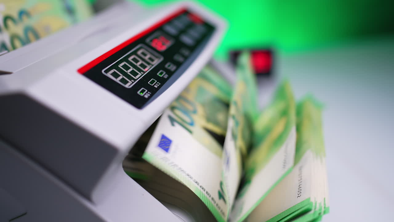 Money counting machine with rotating blades. Hand moves the bills and device quickly counts cash. Close up. Blurred backdrop.