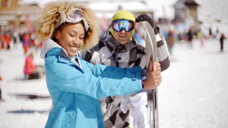 man flirting with woman holding snowboard