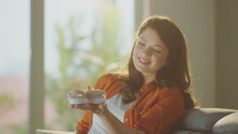 happy pregnant woman holding baby shoes