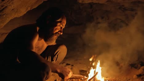 a man sits by a fire in a cave