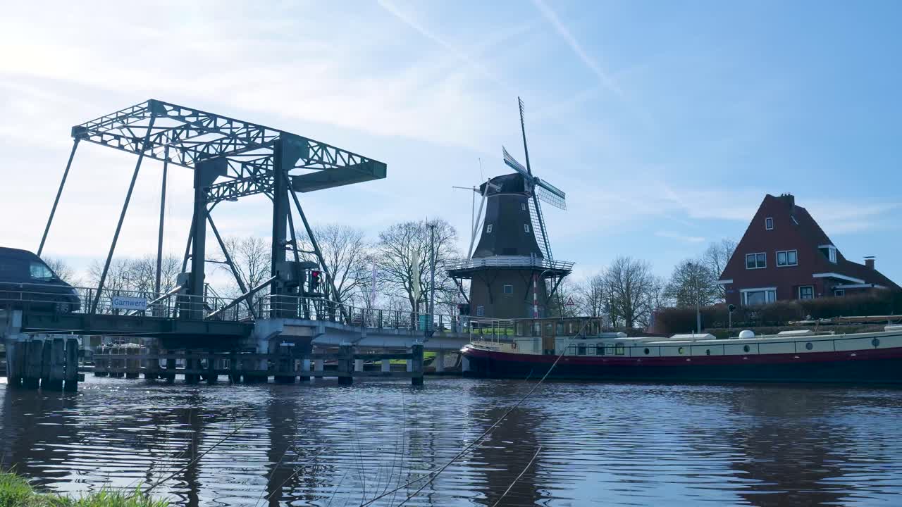 Traditionele Nederlandse windmolen en ophaalbrug over een kanaal met een boot.