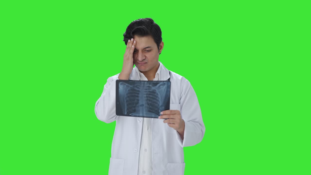 Confused Indian doctor checking X ray report Green screen