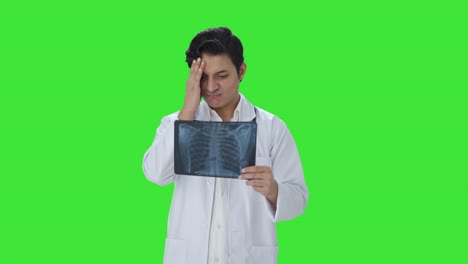 confundido médico indio comprobando el informe de rayos x pantalla verde
