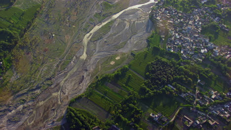 a river and a valley aerial view, green trees, grass and forest with houses, camera is top at the river, water scarcity in the river