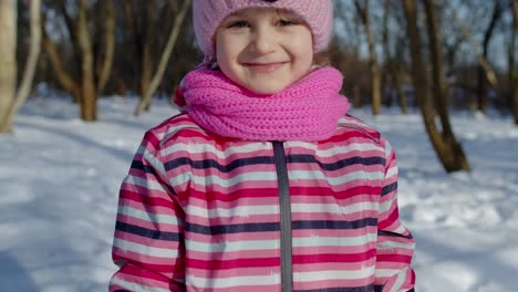 Joyful-little-child-girl-running-towards-on-snowy-road,-looking-at-camera-in-winter-park-forest