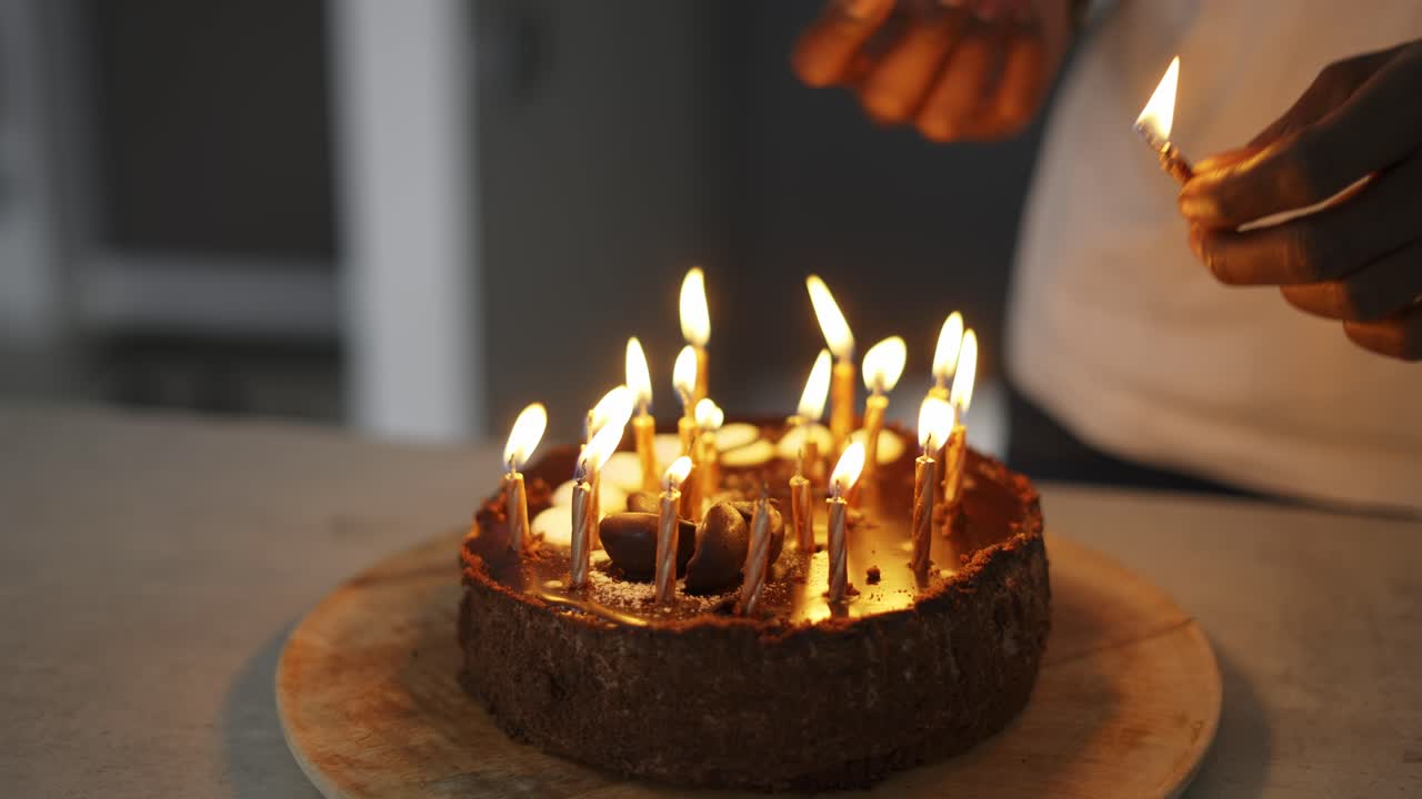 Man's hand lighting candles on birthday cake in a dusk, close up