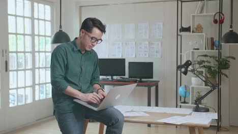 creative designer sits on his desk holds laptop on the knees and working on the project . creative designe and gaming content development studio