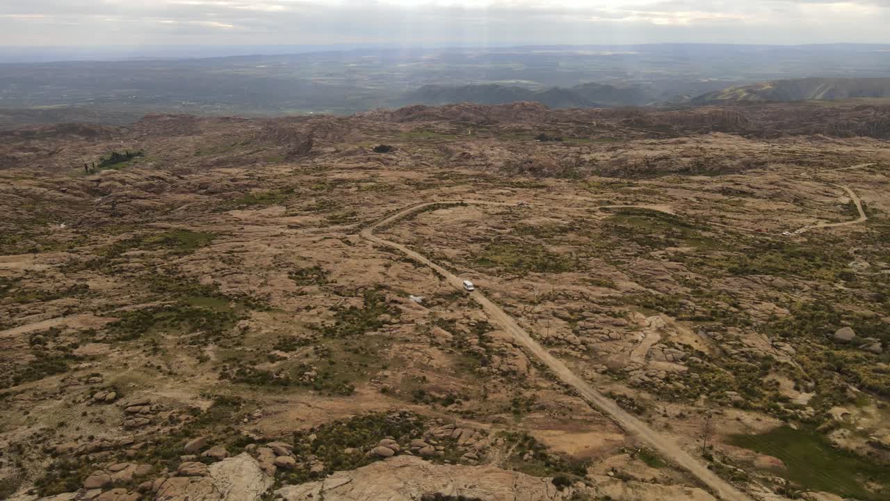 vista aérea de una camioneta turística conduciendo por una carretera rural de montaña en argentina durante la luz del sol