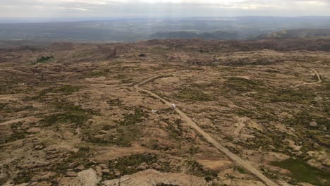 阿根廷在阳光下沿着农村高地公路行驶的旅游货车的空中图