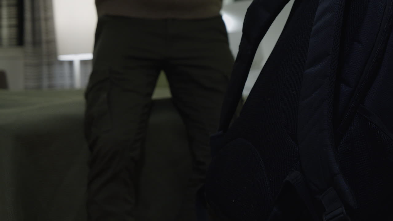 배낭을 메고 지친 남자가 호텔 방에 들어와 침대에 쓰러진다