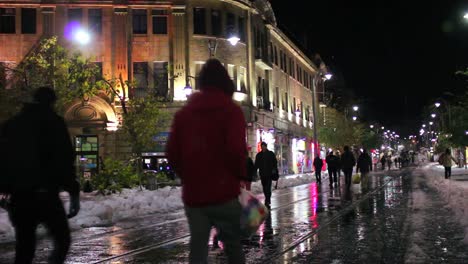 people walk through unusually snowy streets in jerusalem at night