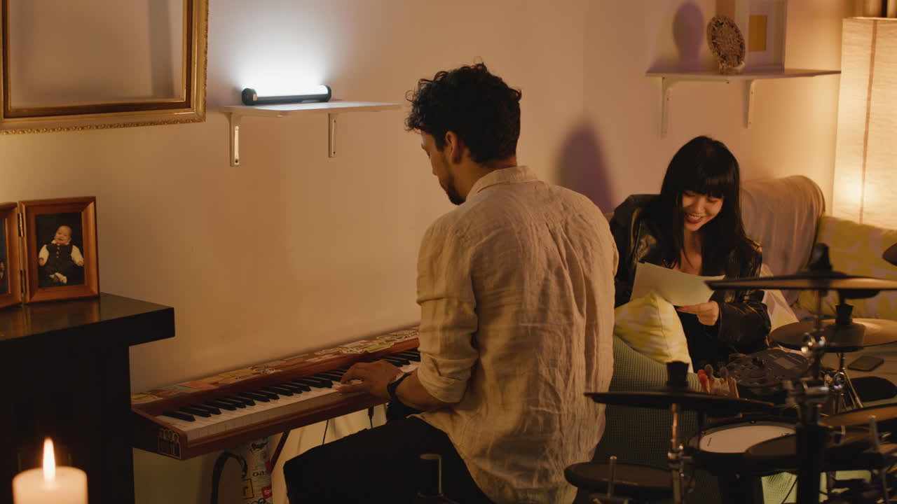 Man playing piano with woman in background
