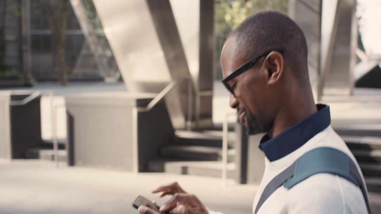 African American businessman walking through city using smart phone