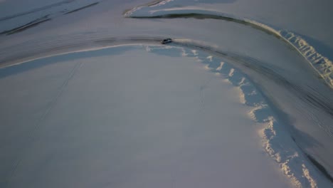 cheap sport cars drifting on frozen lake in finland during golden hour – aerial winter landscape with a frozen race track top down shot