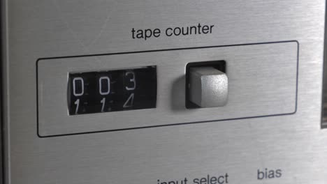 side perspective of stereo hifi casette tape counter counting up with black digit numbers ticking over and silver metal button off to side