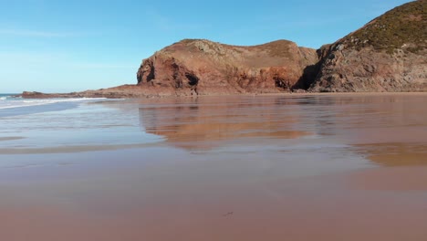 Toma-Aérea-Sobre-Una-Playa-De-Arena-Con-Reflejo-Durante-La-Marea-Baja,-Plemont-Bay,-Jersey,-Islas-Del-Canal,-4k