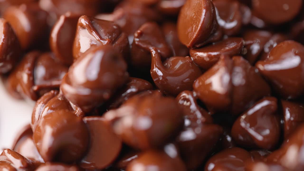 pila de chispas de chocolate semidulce oscuras derretidas calientes que brillan en macro de luz de cerca 4k barrido de luz y pan a la izquierda