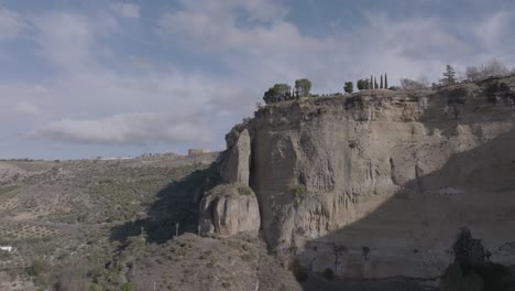 Aerial-flight-to-massive-stone-pillar,-vertical-cliffs-in-Ronda,-Spain