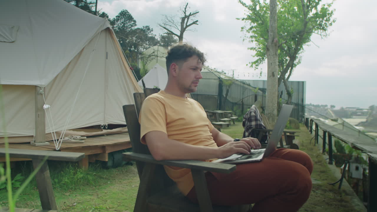 Man Working on Laptop Outdoors at Glamping