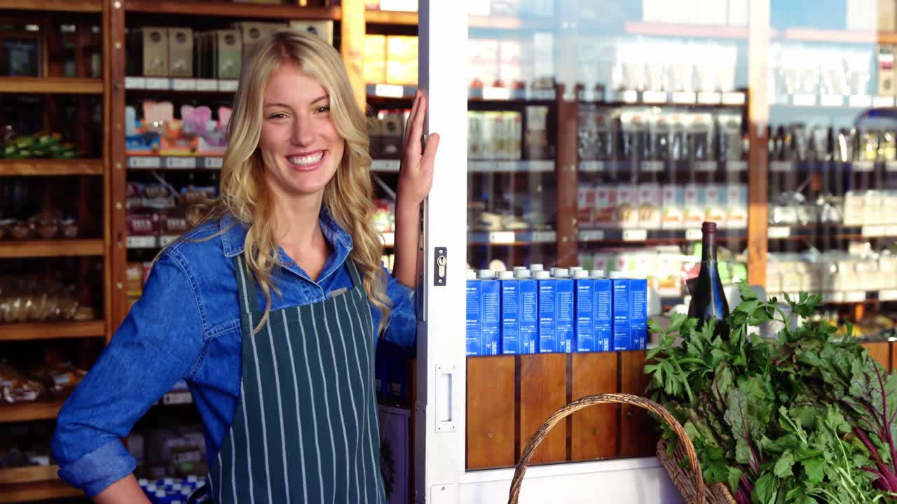 Proprietario sorridente in piedi accanto a un'insegna aperta in un supermercato.