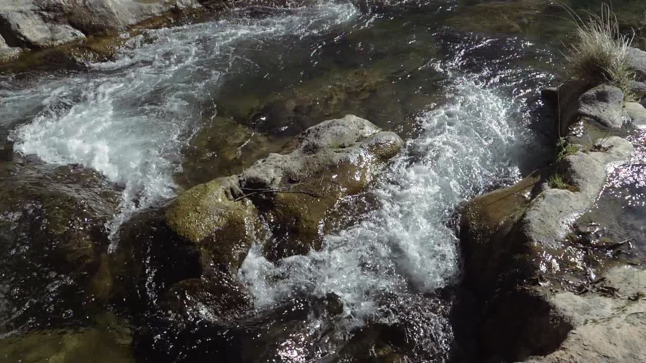 Um rio caudaloso fluindo rio abaixo é dividido em dois caminhos por uma grande rocha na água.