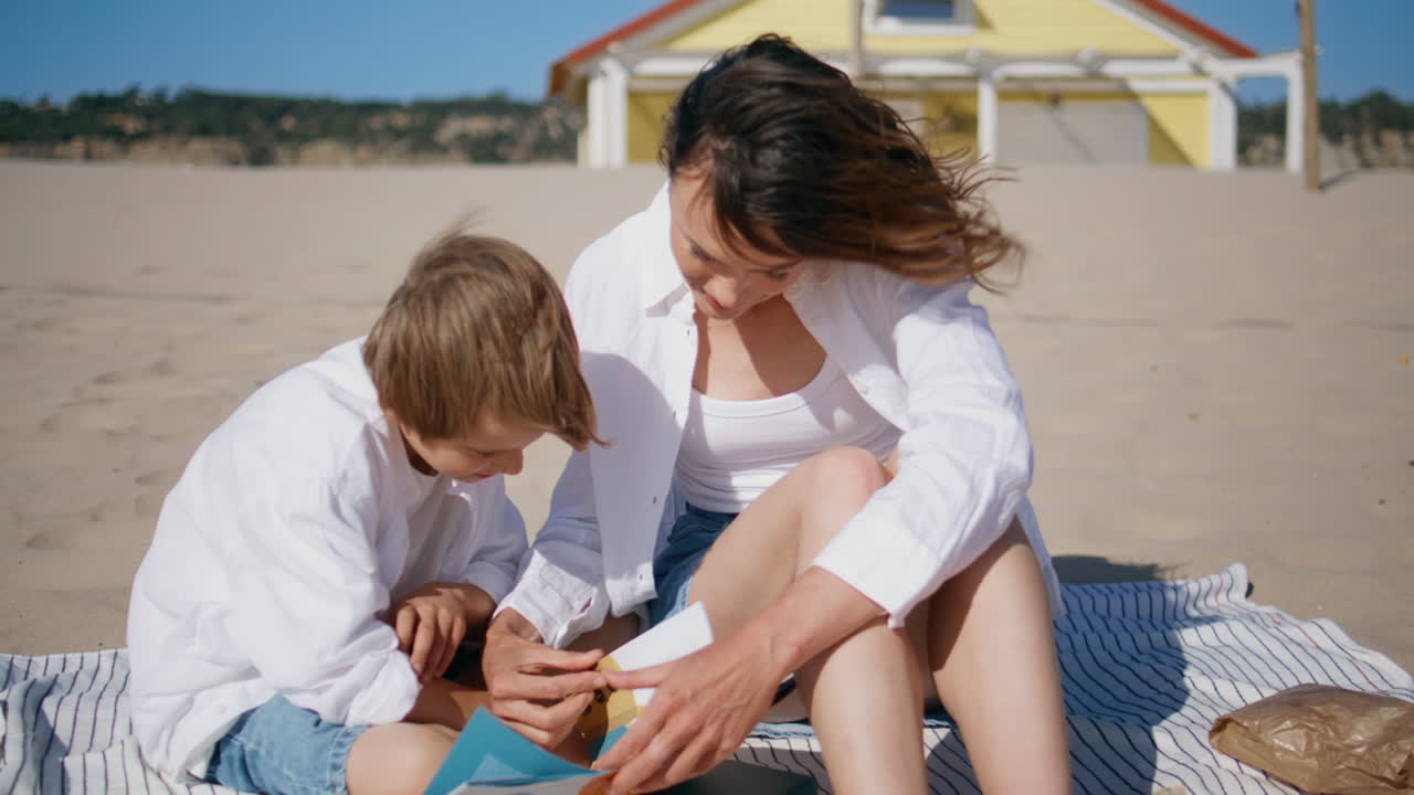 Mom son reading book on sunny windy beach. Family bonding over fairy tales