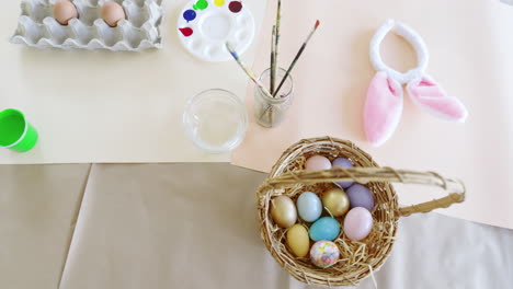 easter, eggs in carton surrounded by colorful paints and brushes on table, at home