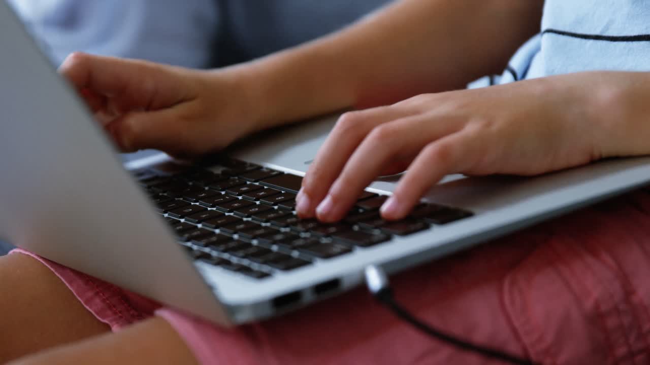 sección media del niño usando computadora portátil en la sala de estar